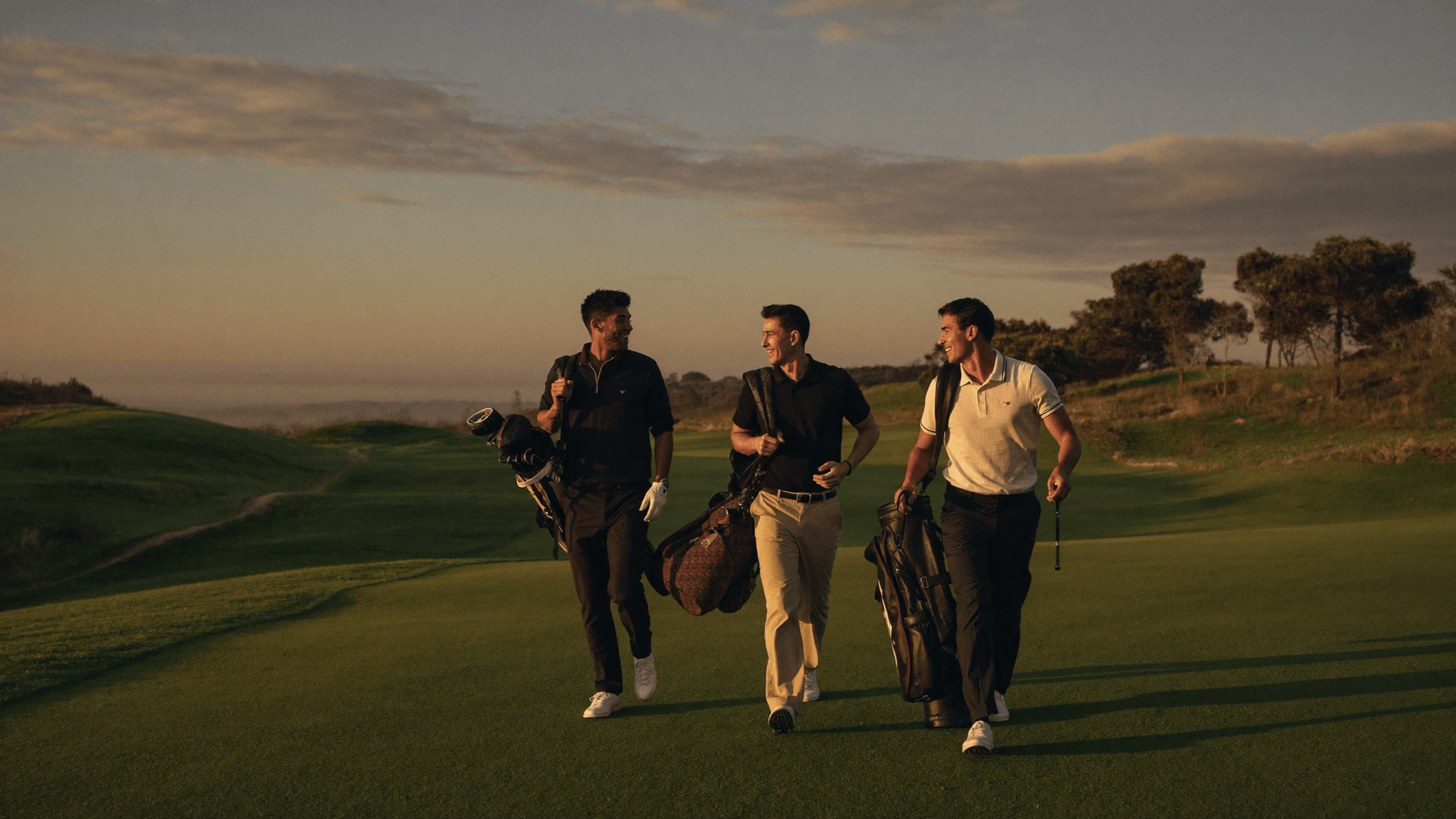 Golfers wearing House of Par clothing walking on a links course at sunrise