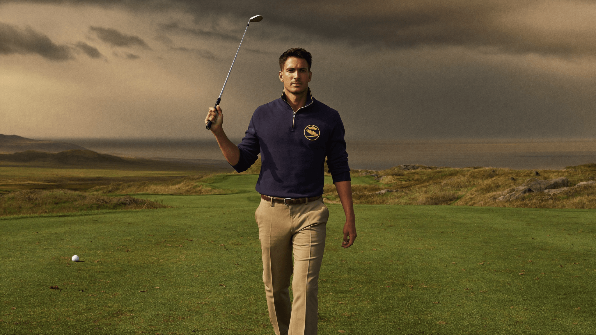 Golfer wearing House of Par apparel walking on a British links course at golden hour
